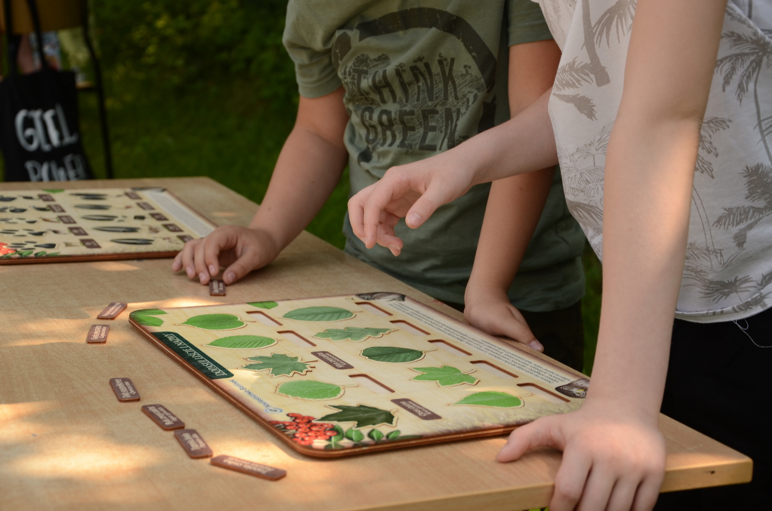 Na zdjęciu widać dłonie uczniów oraz puzzle o tematyce leśnej "Jaki to liść".